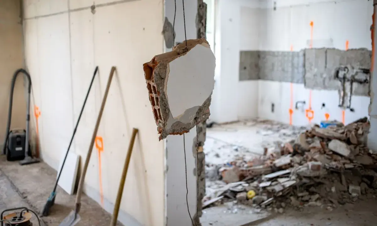 Demolizione di un muro interno, con detriti e attrezzi da lavoro. L'abbattimento muro interno senza CILA è un'operazione delicata.