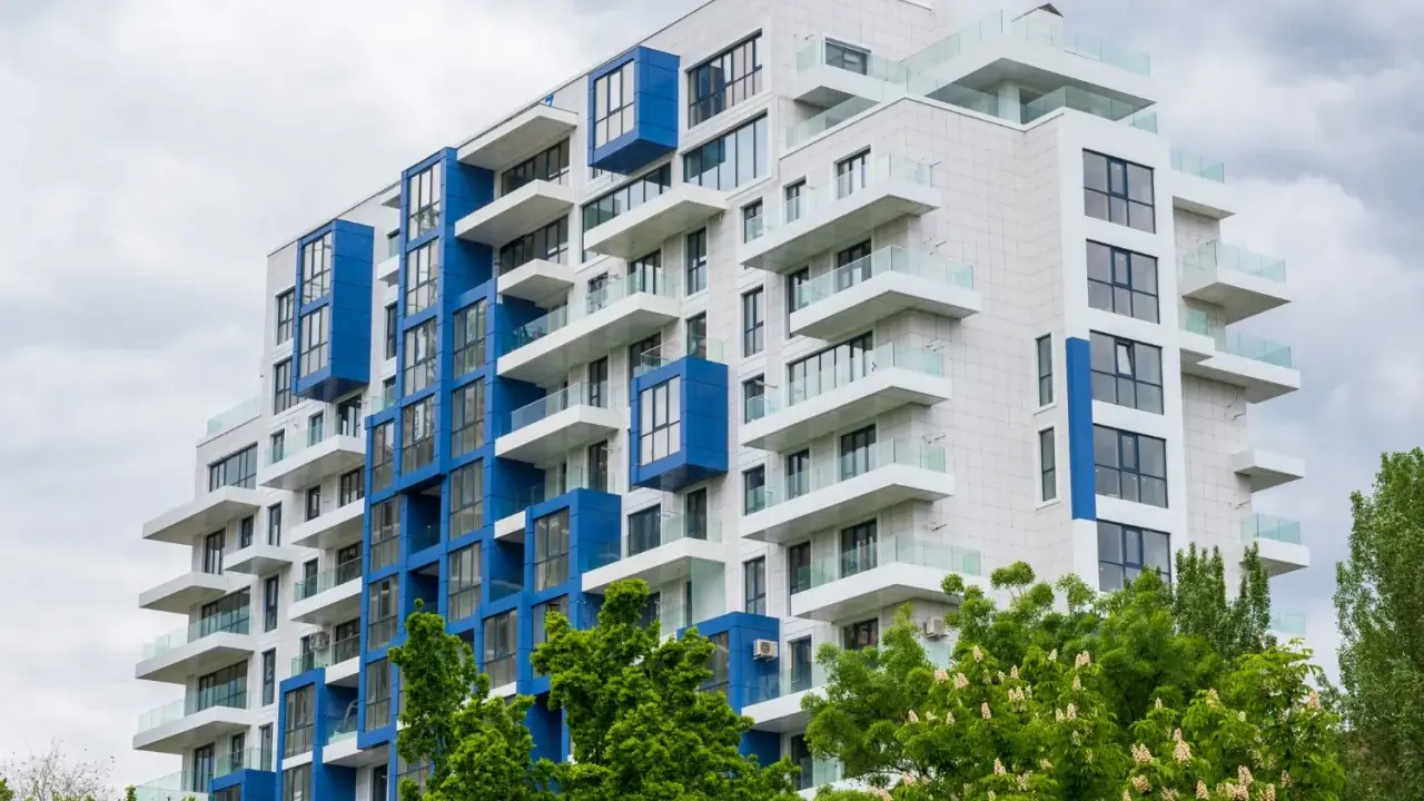 Moderno palazzo con balconi bianchi e blu, un esempio di edilizia popolare dal design accattivante.