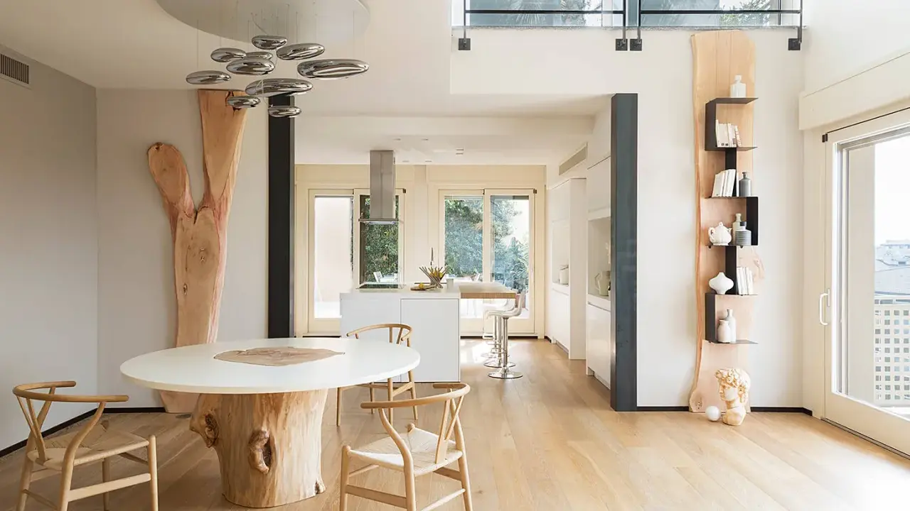 Interni case in legno moderne con tavolo scultoreo e cucina a vista.