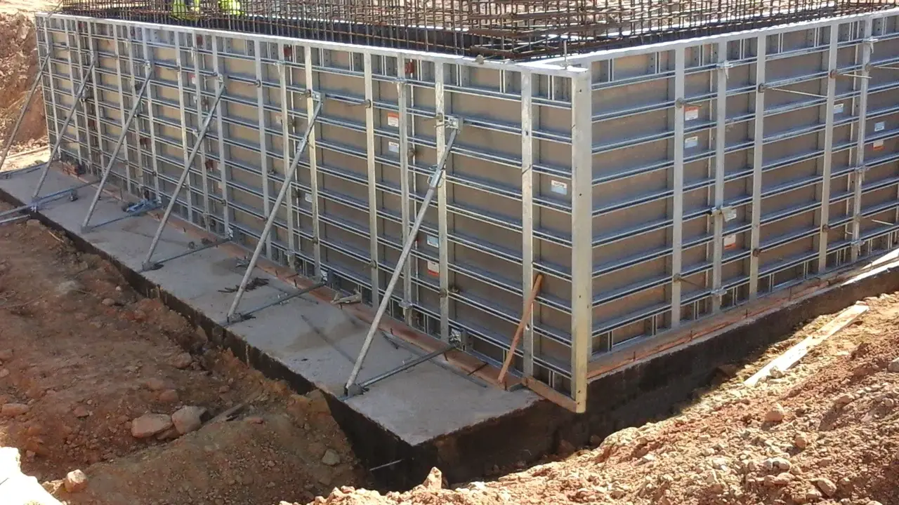 Casse edili metalliche montate per gettare una fondazione in cemento armato, con armature metalliche visibili in alto.