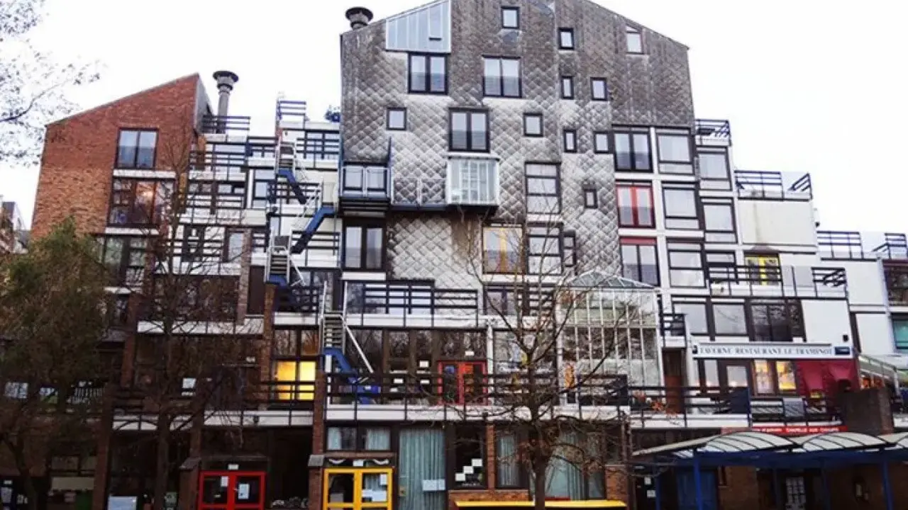 Edificio residenziale con facciata a mosaico, balconi e scale esterne, un esempio di architettura di Lucien Kroll.