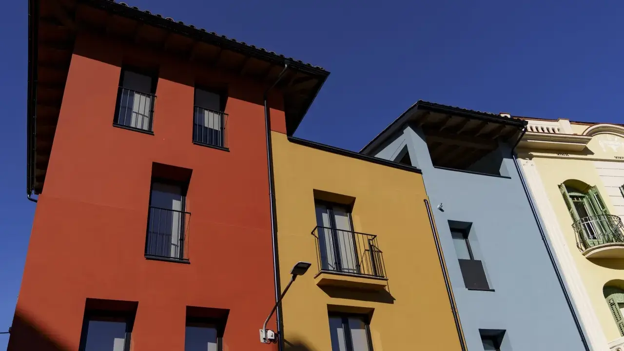 Edifici colorati con facciata giallo ocra, rosso e azzurro sotto un cielo limpido.