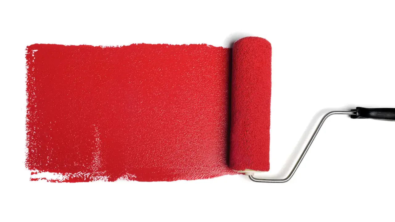 Rullo da pittura stende una striscia di vernice rosso antico, ideale per il colore esterno di una casa.