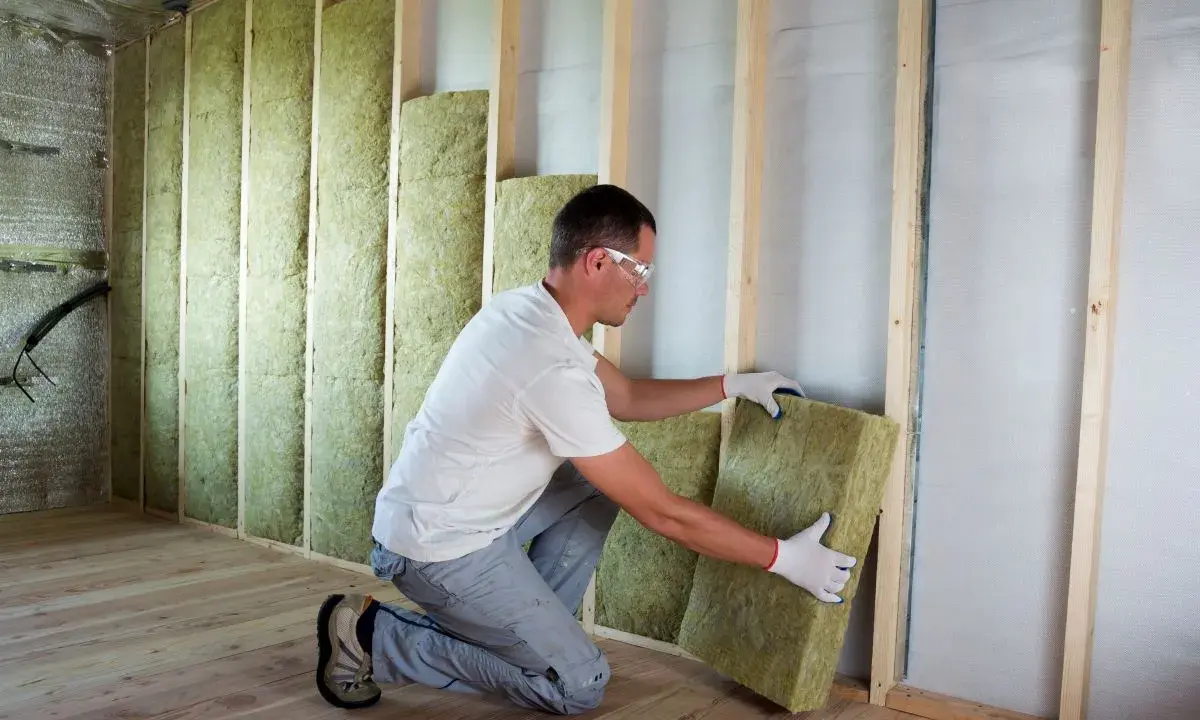 Operaio posiziona pannelli in fibra di legno per cappotto interno, creando un ambiente più confortevole e isolato.