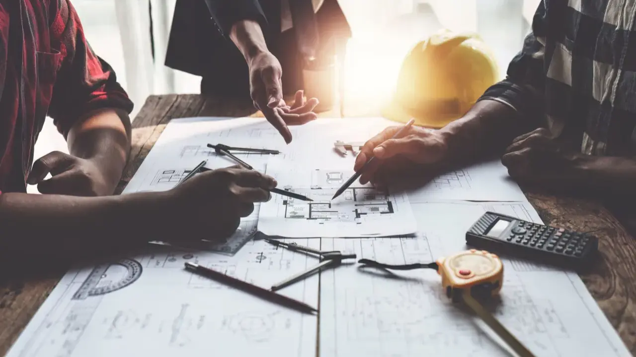 Architetti discutono progetti, cercando soluzioni per sanare un abuso edilizio commesso dal precedente proprietario.