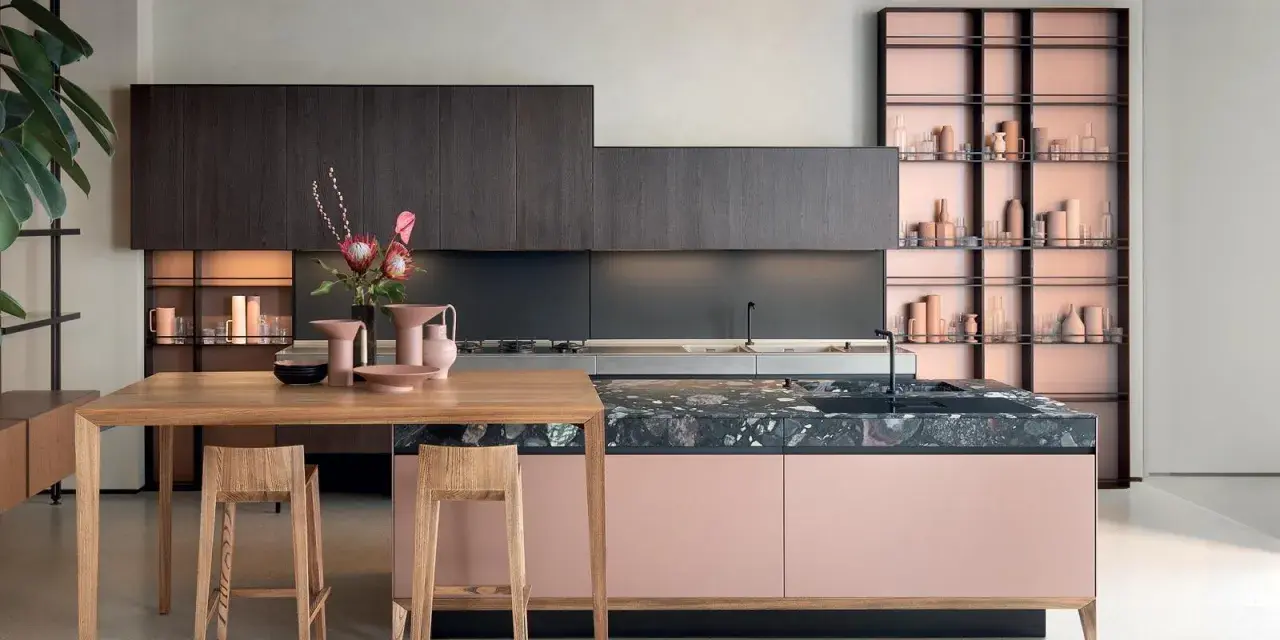 Cucine moderne con un mix di colori audaci: ante rosa cipria, top in marmo scuro e scaffalature color rame.