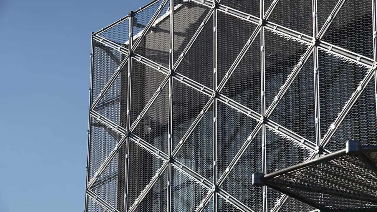Struttura geometrica di un edificio moderno con pannelli a rete metallica, esempio di materiali da costruzione innovativi.