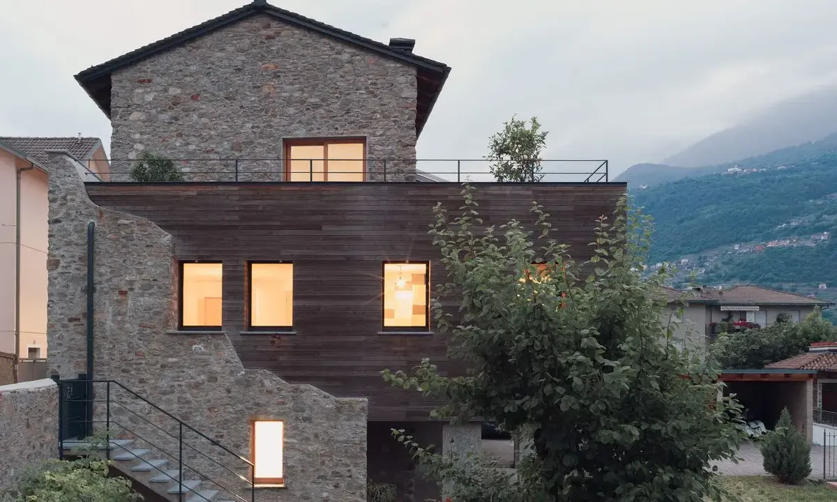 Facciate case di campagna esterni con pietra e legno, un connubio tra antico e moderno. Scale esterne conducono a un tetto-terrazza.