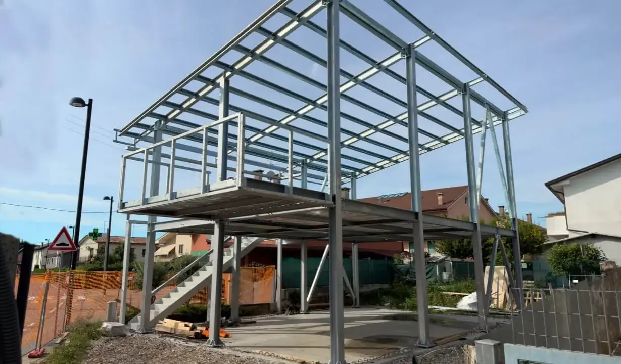 Struttura in acciaio per una casa in costruzione, con impalcati e tettoia visibili. Nessun difetto casa in acciaio evidente in questa fase.