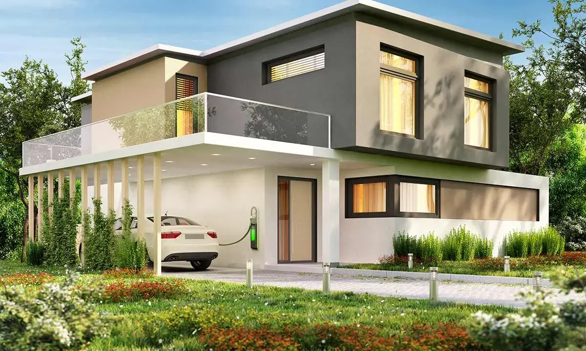 Casa moderna con tetto piano, balcone in vetro e un'auto bianca in carica. Il colore esterno casa verde si integra con il giardino lussureggiante.
