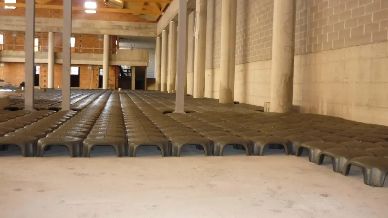 Struttura in costruzione con file di elementi prefabbricati che creano un vuoto sanitario. Colonne e pareti in mattoni visibili.