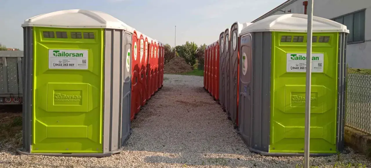 File di bagni chimici portatili, verdi e rossi, pronti per essere installati. Servizi igienici normativa rispettata.