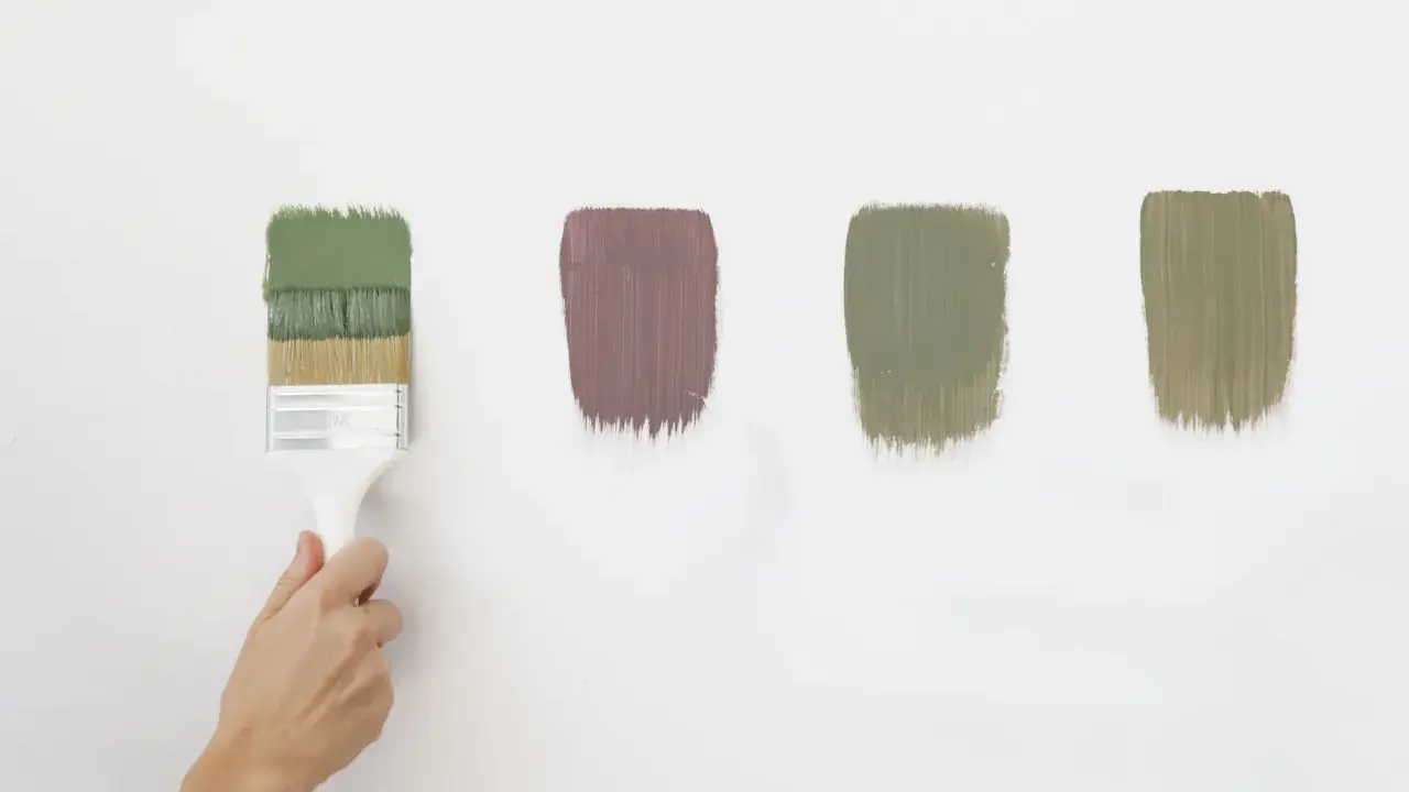 Pennello con vernici ecologiche in diverse tonalità di verde e un tocco di malva su sfondo bianco.