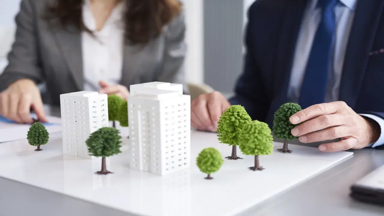 Modelli di edifici e alberi su un tavolo, che illustrano il **social housing significato** e la pianificazione urbana sostenibile.