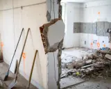 Demolizione di un muro interno, con detriti e attrezzi da lavoro. L'abbattimento muro interno senza CILA è un'operazione delicata.