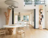 Interni case in legno moderne con tavolo scultoreo e cucina a vista.