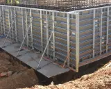 Casse edili metalliche montate per gettare una fondazione in cemento armato, con armature metalliche visibili in alto.