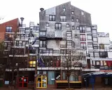 Edificio residenziale con facciata a mosaico, balconi e scale esterne, un esempio di architettura di Lucien Kroll.