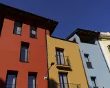 Edifici colorati con facciata giallo ocra, rosso e azzurro sotto un cielo limpido.