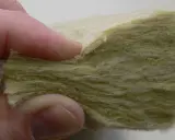 Dita che toccano un campione di lana di roccia, materiale isolante per eccellenza.
