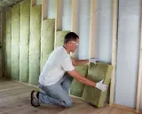Operaio posiziona pannelli in fibra di legno per cappotto interno, creando un ambiente più confortevole e isolato.