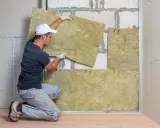 Operaio posiziona pannelli per isolamento termico soffitto dall'interno. Lavori di ristrutturazione in corso.