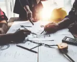 Architetti discutono progetti, cercando soluzioni per sanare un abuso edilizio commesso dal precedente proprietario.