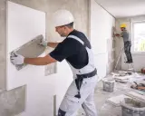 Operai applicano pannelli per l'isolamento termico delle pareti, un passo fondamentale per il comfort e il risparmio energetico.