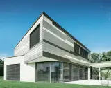 Moderna casa con pareti esterne a fasce grigie e bianche, grandi finestre con persiane e prato verde.
