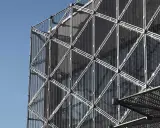 Struttura geometrica di un edificio moderno con pannelli a rete metallica, esempio di materiali da costruzione innovativi.