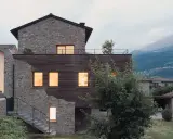 Facciate case di campagna esterni con pietra e legno, un connubio tra antico e moderno. Scale esterne conducono a un tetto-terrazza.