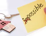 Chiavi di casa con portachiavi a forma di casetta. Post-it giallo con "impossible" barrato, simboleggia che l'edilizia convenzionata pro e contro può diventare possibile.