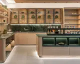 Una cucina moderna con un'isola centrale. Il piano di lavoro e il paraschizzi in marmo verde creano un contrasto elegante con le ante in legno chiaro. Il colore verde domina, donando un tocco di natura e raffinatezza.