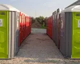 File di bagni chimici portatili, verdi e rossi, pronti per essere installati. Servizi igienici normativa rispettata.
