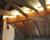 Soffitto in legno con travetti a vista, illuminato da luce naturale. Si nota una libreria e pareti in pietra. La lunghezza massima travetti solaio è ben visibile.