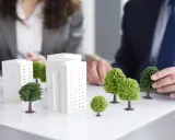 Modelli di edifici e alberi su un tavolo, che illustrano il **social housing significato** e la pianificazione urbana sostenibile.