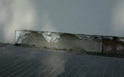 Dettaglio di un muro con isolamento danneggiato, mostrando la differenza tra xps e eps. Grata metallica in primo piano.