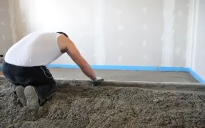 Operaio al lavoro per stendere il massetto edilizia, creando una base solida per il pavimento.