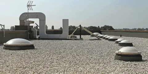 Tetto piano ricoperto di ghiaia, con lucernari a cupola e condotti di ventilazione. Il vespaio ghiaia protegge la copertura.