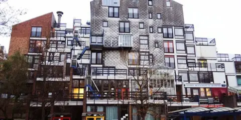 Edificio residenziale con facciata a mosaico, balconi e scale esterne, un esempio di architettura di Lucien Kroll.