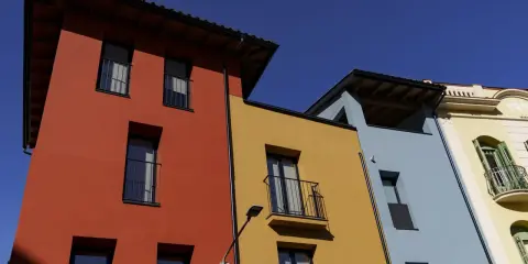 Edifici colorati con facciata giallo ocra, rosso e azzurro sotto un cielo limpido.