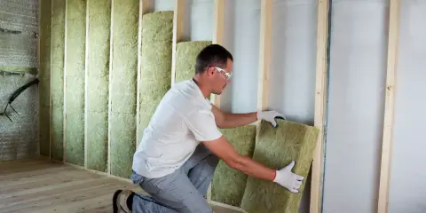 Operaio posiziona pannelli in fibra di legno per cappotto interno, creando un ambiente più confortevole e isolato.