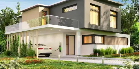 Casa moderna con tetto piano, balcone in vetro e un'auto bianca in carica. Il colore esterno casa verde si integra con il giardino lussureggiante.