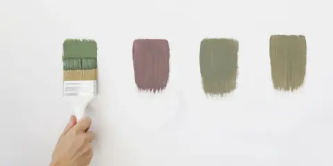 Pennello con vernici ecologiche in diverse tonalità di verde e un tocco di malva su sfondo bianco.