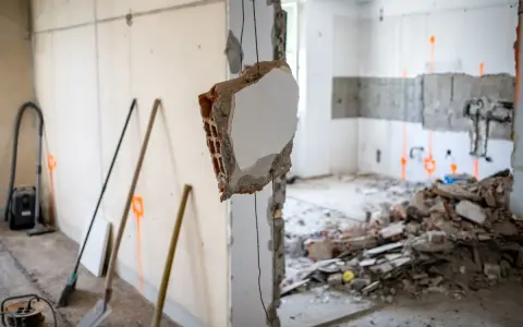 Demolizione di un muro interno, con detriti e attrezzi da lavoro. L'abbattimento muro interno senza CILA è un'operazione delicata.