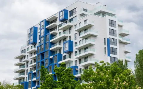 Moderno palazzo con balconi bianchi e blu, un esempio di edilizia popolare dal design accattivante.