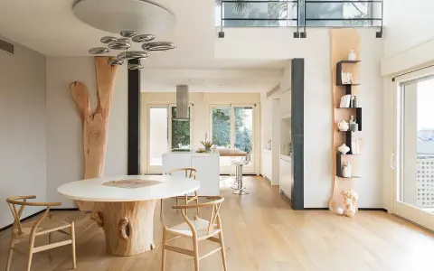 Interni case in legno moderne con tavolo scultoreo e cucina a vista.