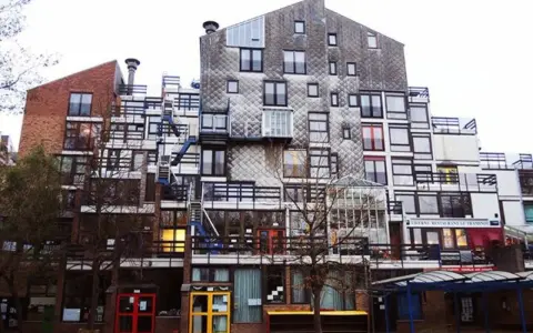 Edificio residenziale con facciata a mosaico, balconi e scale esterne, un esempio di architettura di Lucien Kroll.