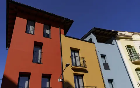 Edifici colorati con facciata giallo ocra, rosso e azzurro sotto un cielo limpido.