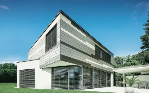 Moderna casa con pareti esterne a fasce grigie e bianche, grandi finestre con persiane e prato verde.
